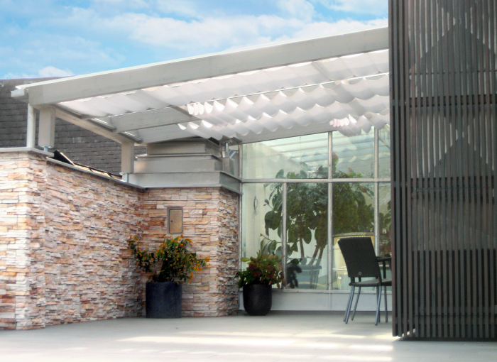 Modernes Terrassendach aus Holz und Glas mit Beschattung und vorvergrauter Holzfassade in heimischer Lärche