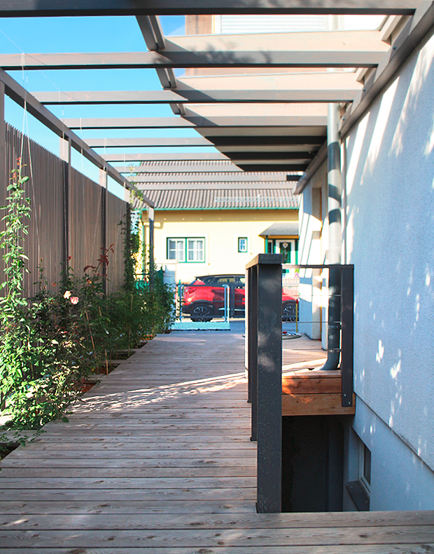 Modern und zeitlos in Holz: Pergola in Lärche grau geölt mit transparentem Sichtschutz mit vertikalen Lamellen / Holzleisten